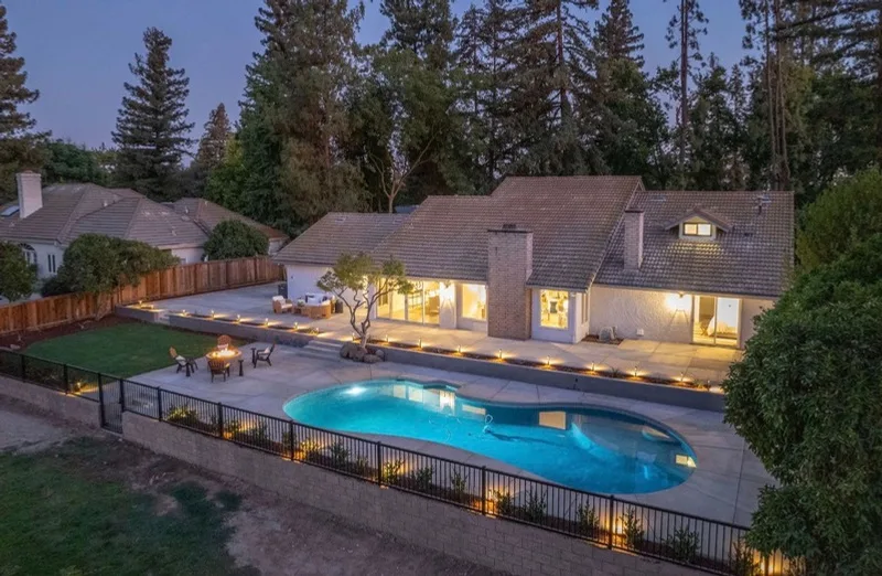 Backyard after at dusk, rebuilt pool with landscape lighting