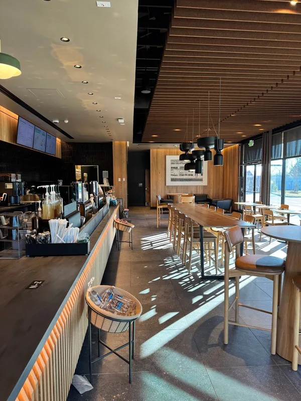 Inside the new cafe: wood slat ceiling, long communal table, and morning light